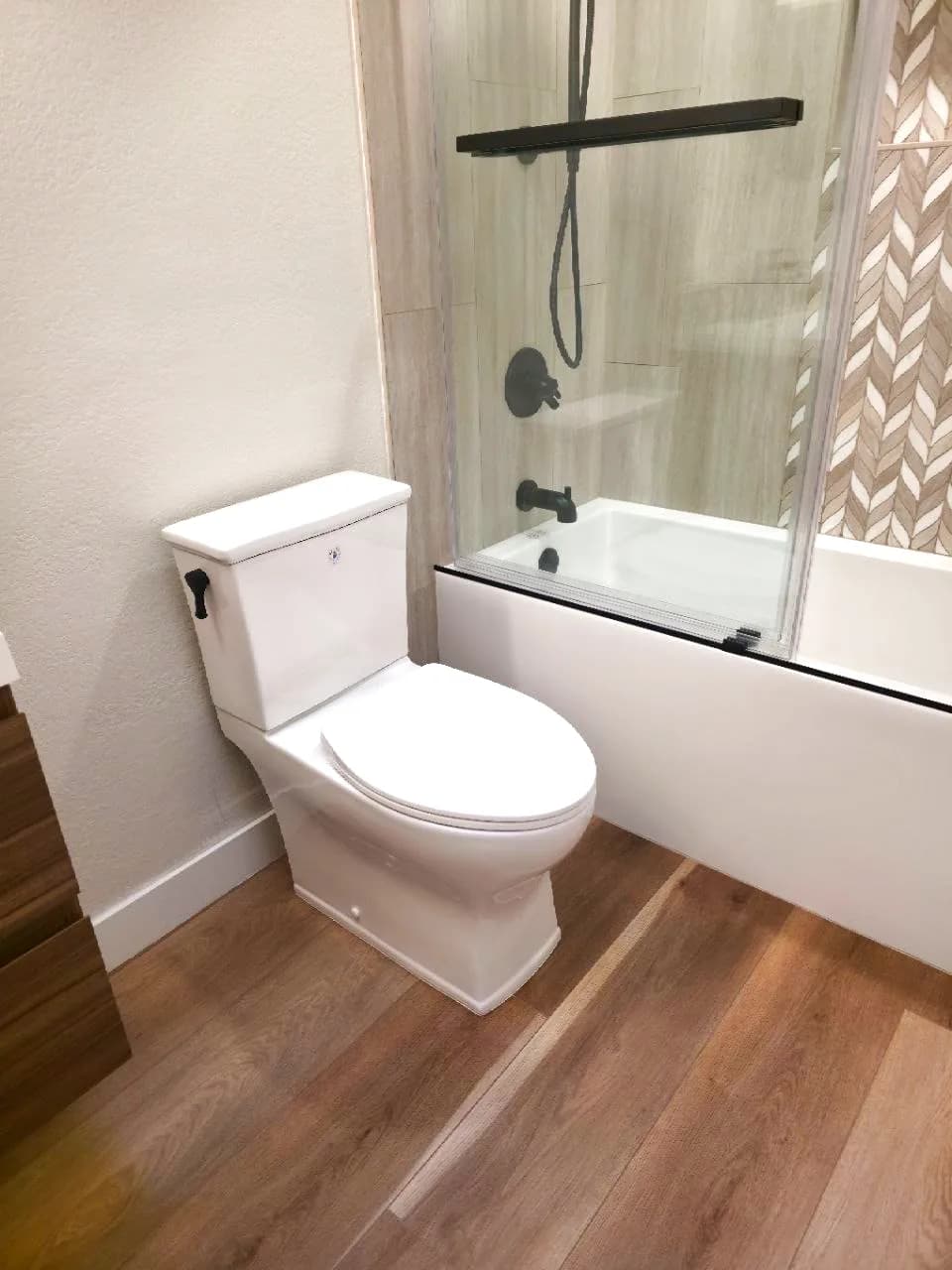 After: skirted toilet, wood-look plank floor and the new tub-shower