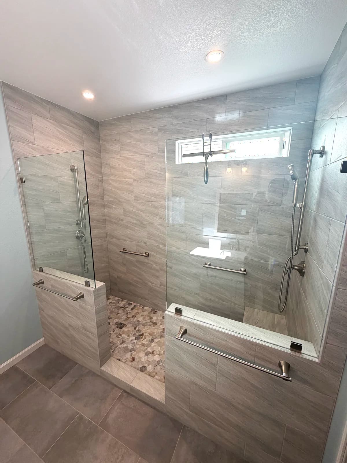 After: large walk-in shower with grey porcelain tile, pebble accent wall and frameless glass in Citrus Heights, CA
