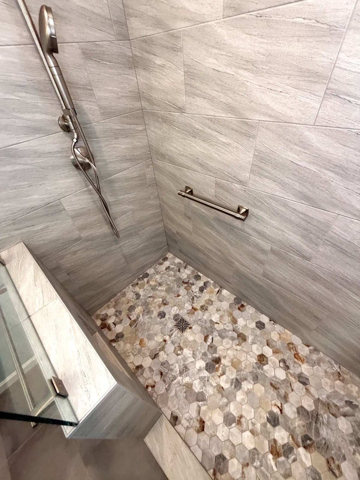 After: natural pebble stone accent wall and tiled bench inside the shower