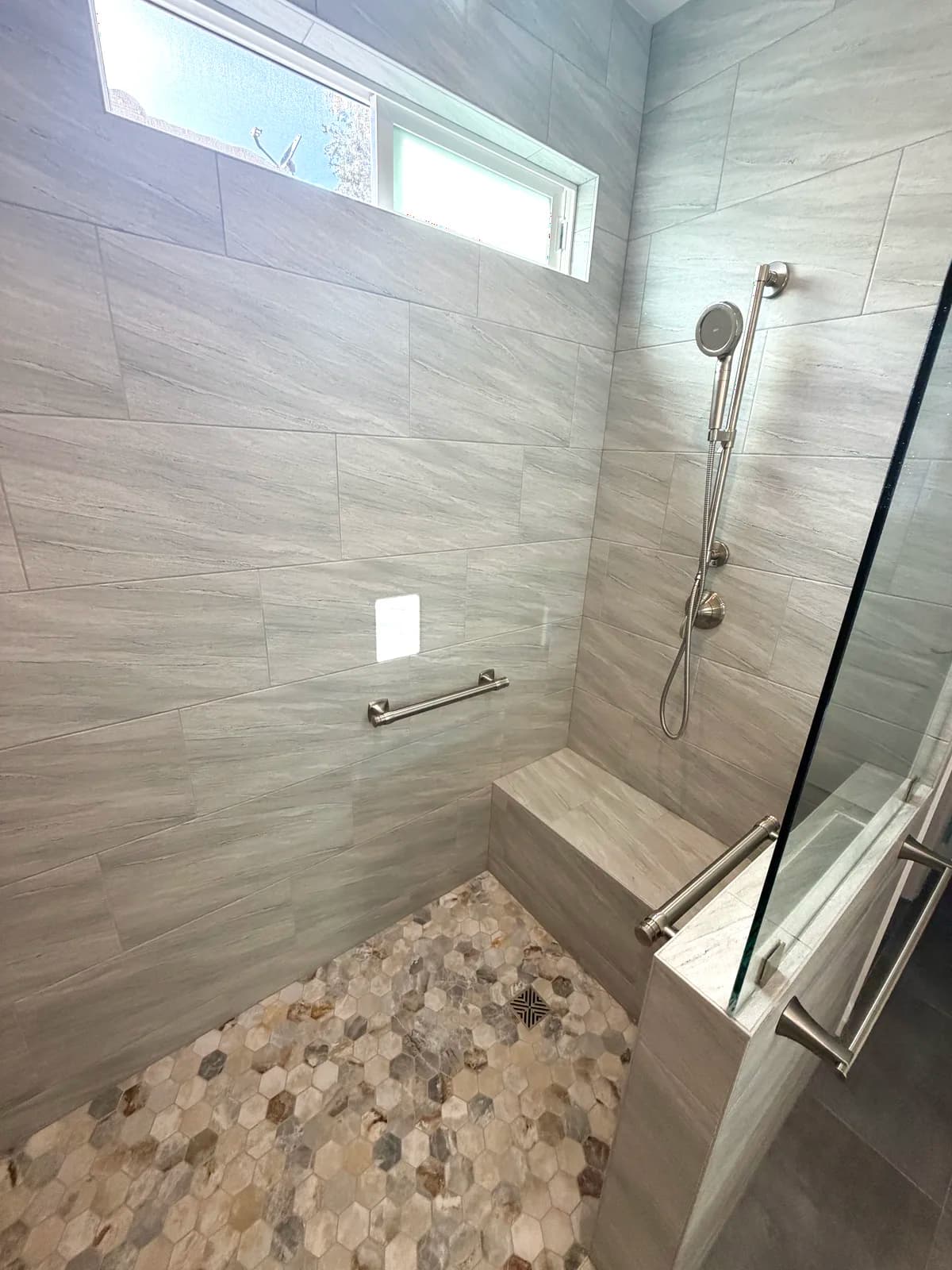 After: two shower stations with handhelds on slide bars seen through the glass panel