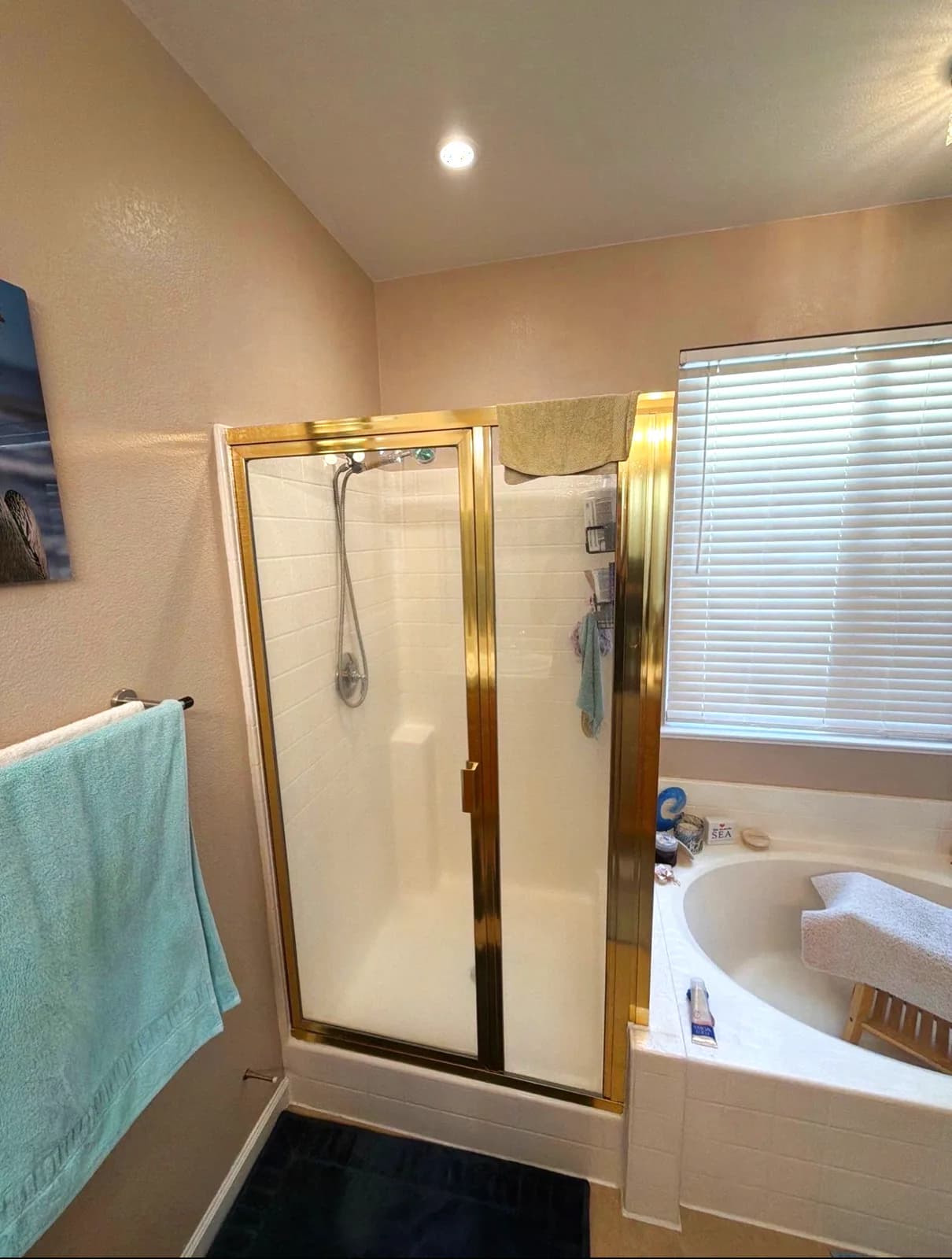Before: corner drop-in tub under the window with tan tile deck