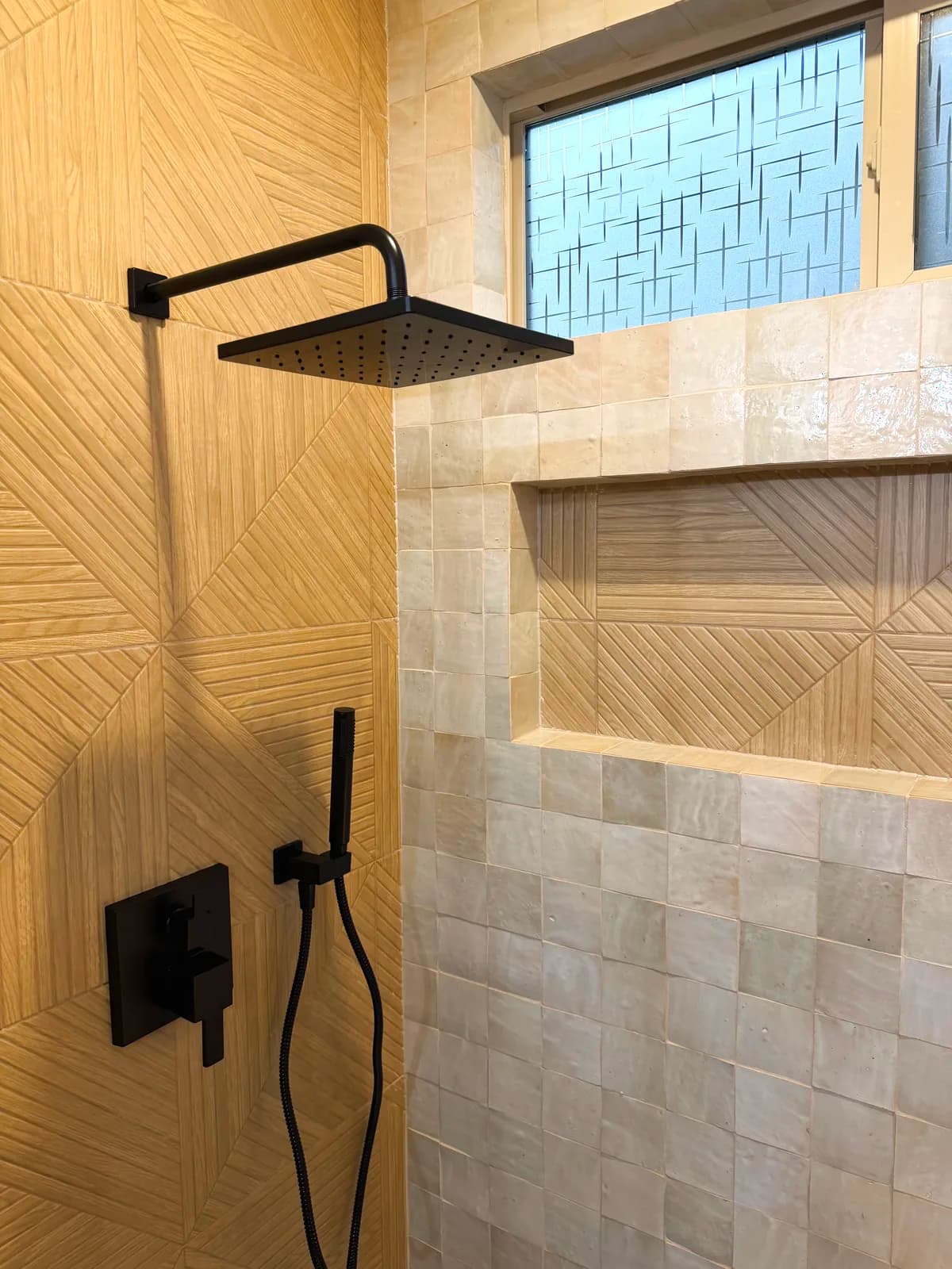 After: matte black rain head and handheld over a wood-look chevron shower floor