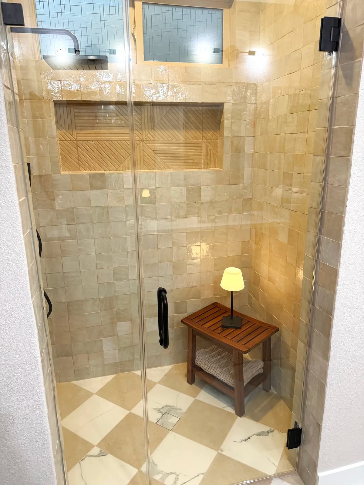 After: teak bench with black wall sconce and recessed niche inside the shower
