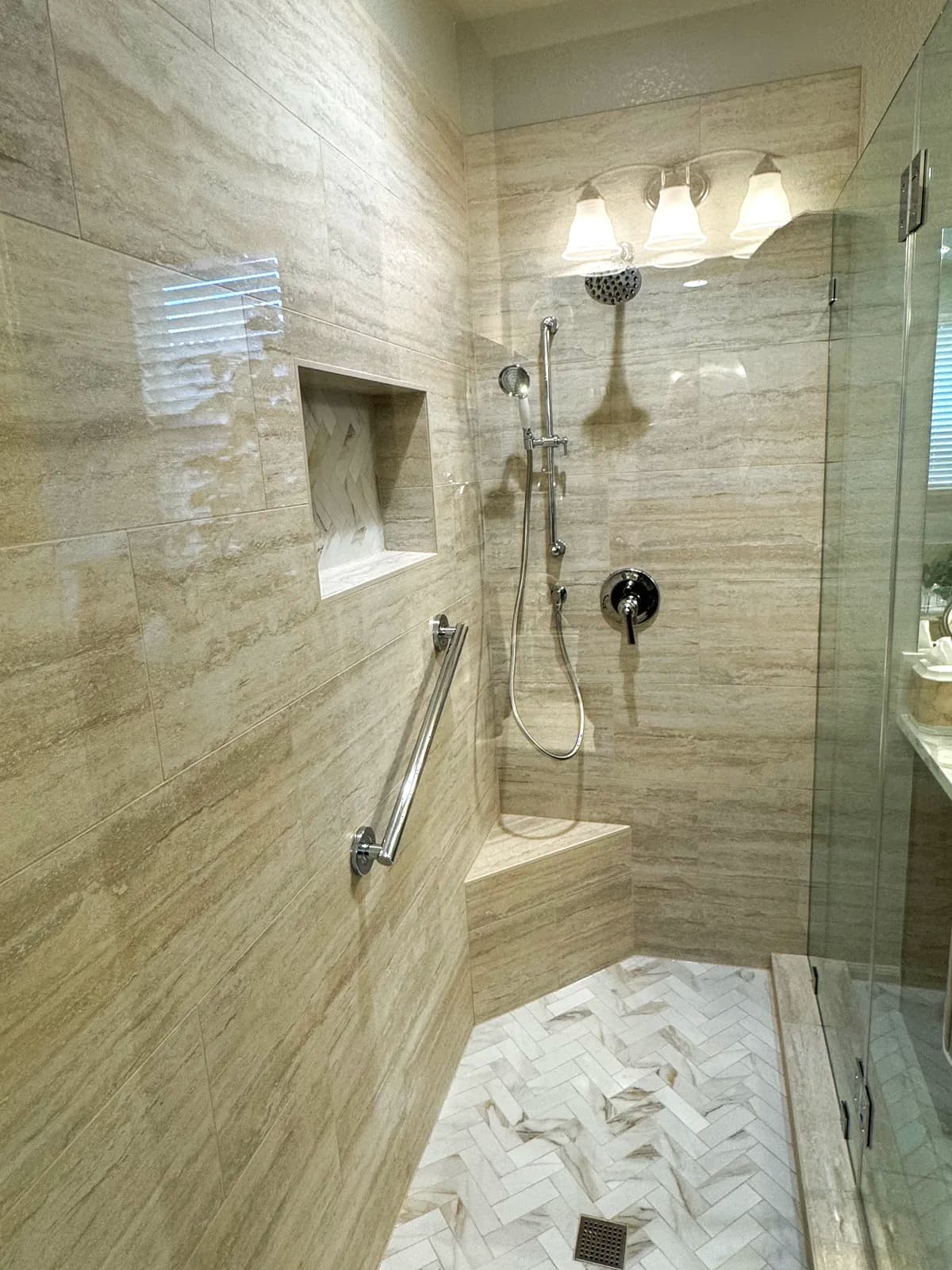 After: walk-in shower with travertine-look porcelain, herringbone marble accent wall and frameless glass in El Dorado Hills, CA