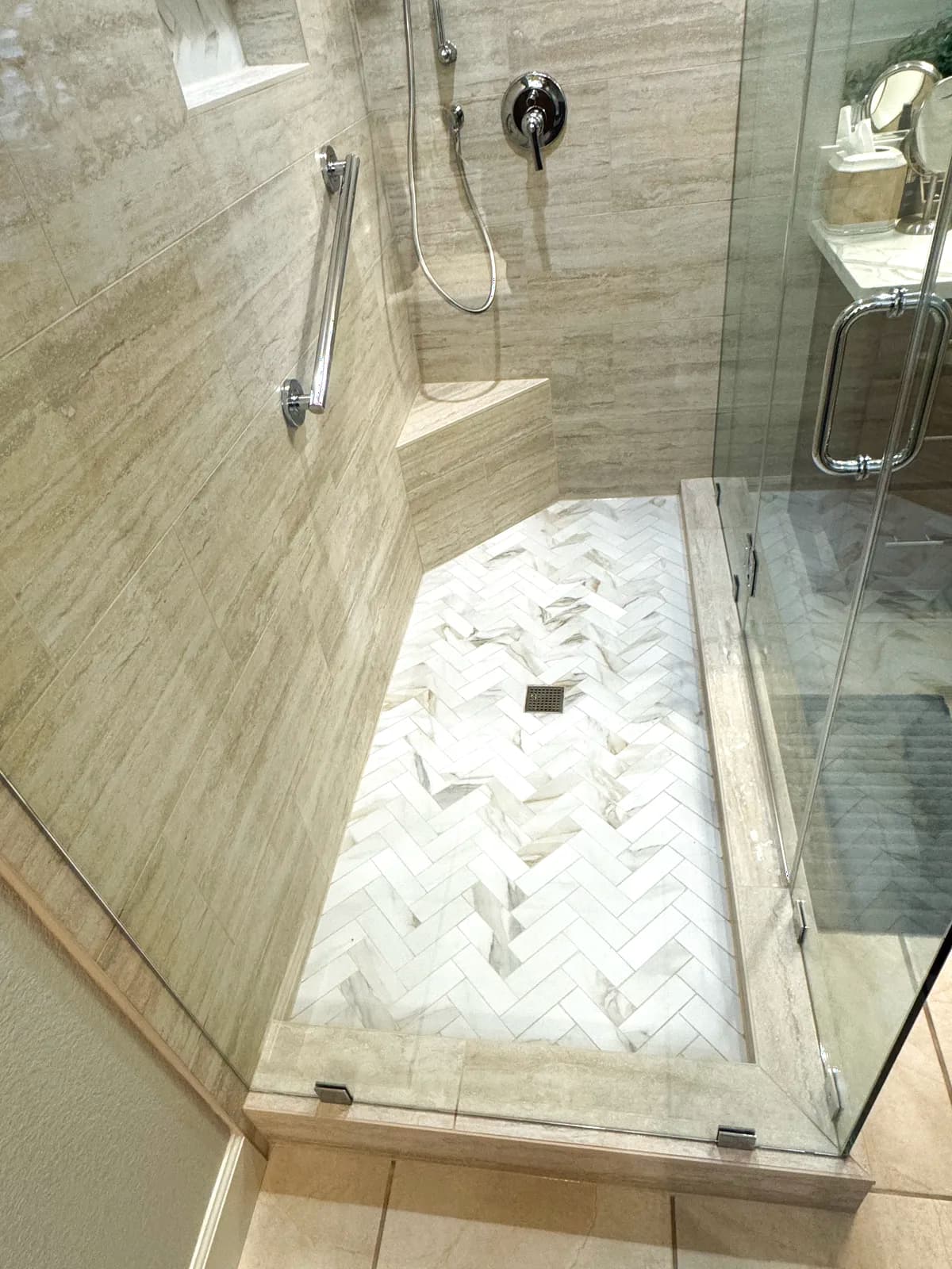 After: herringbone marble accent wall and grab bar inside the shower