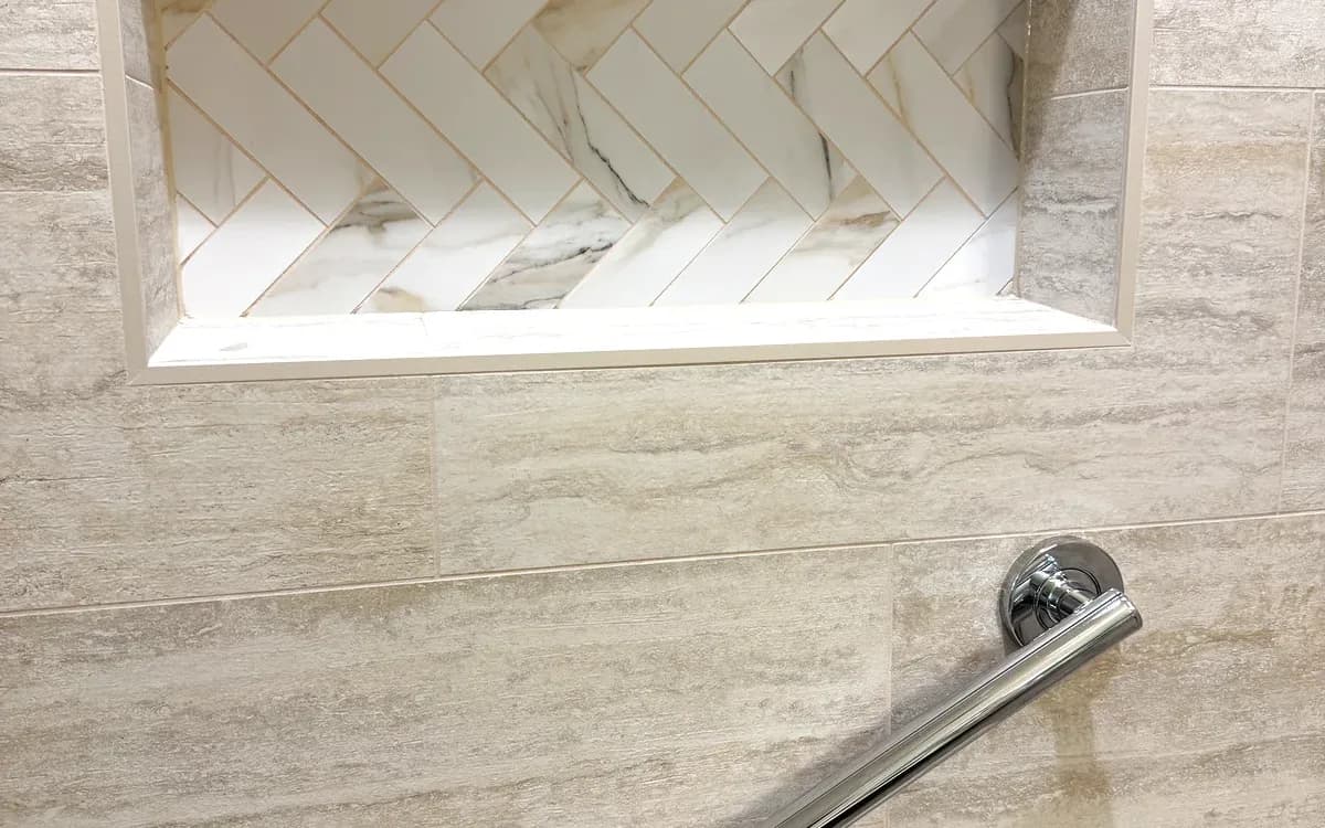 Close-up of the marble-lined niche and brushed nickel grab bar