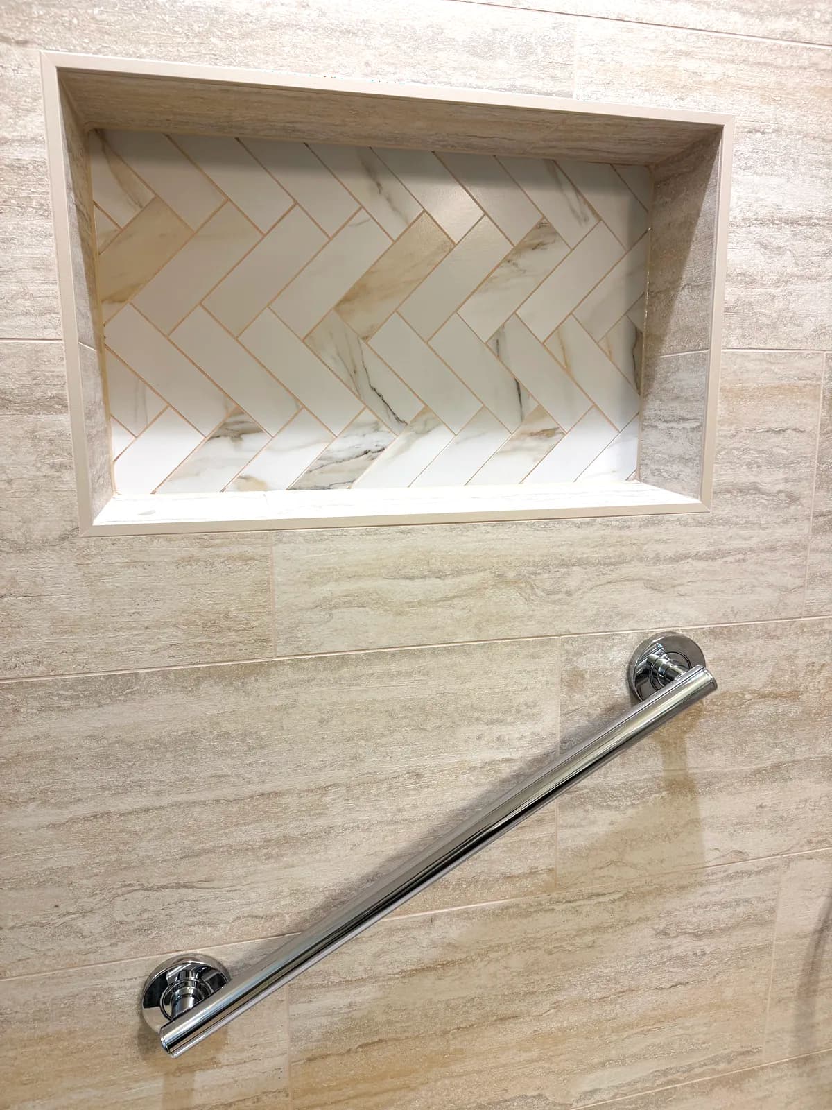 After: close-up of the marble-lined niche and brushed nickel grab bar