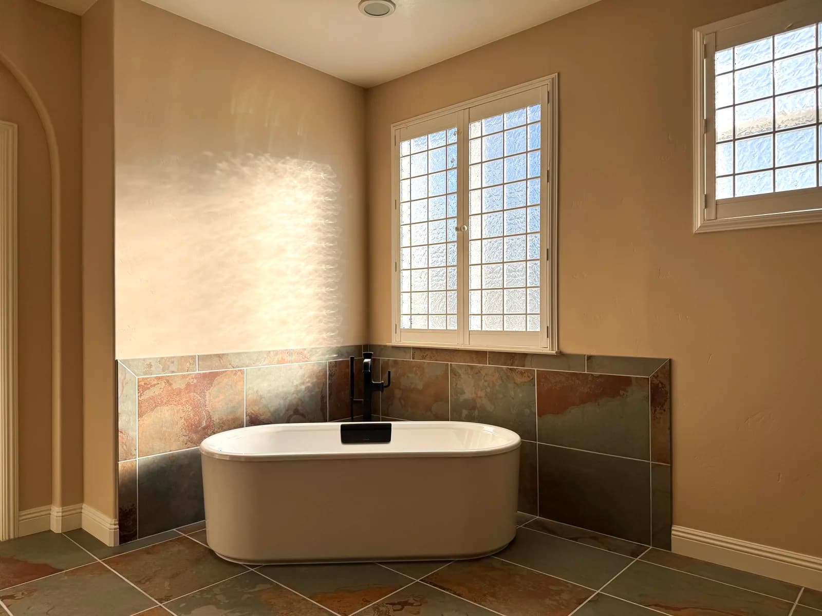After: freestanding tub under the windows with slate-look porcelain wainscot in Elk Grove, CA