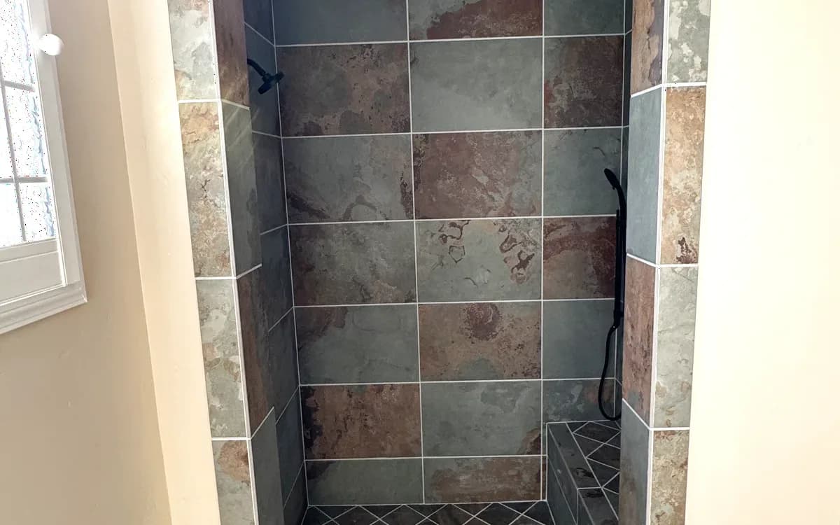Arched shower opening finished in slate-look porcelain tile