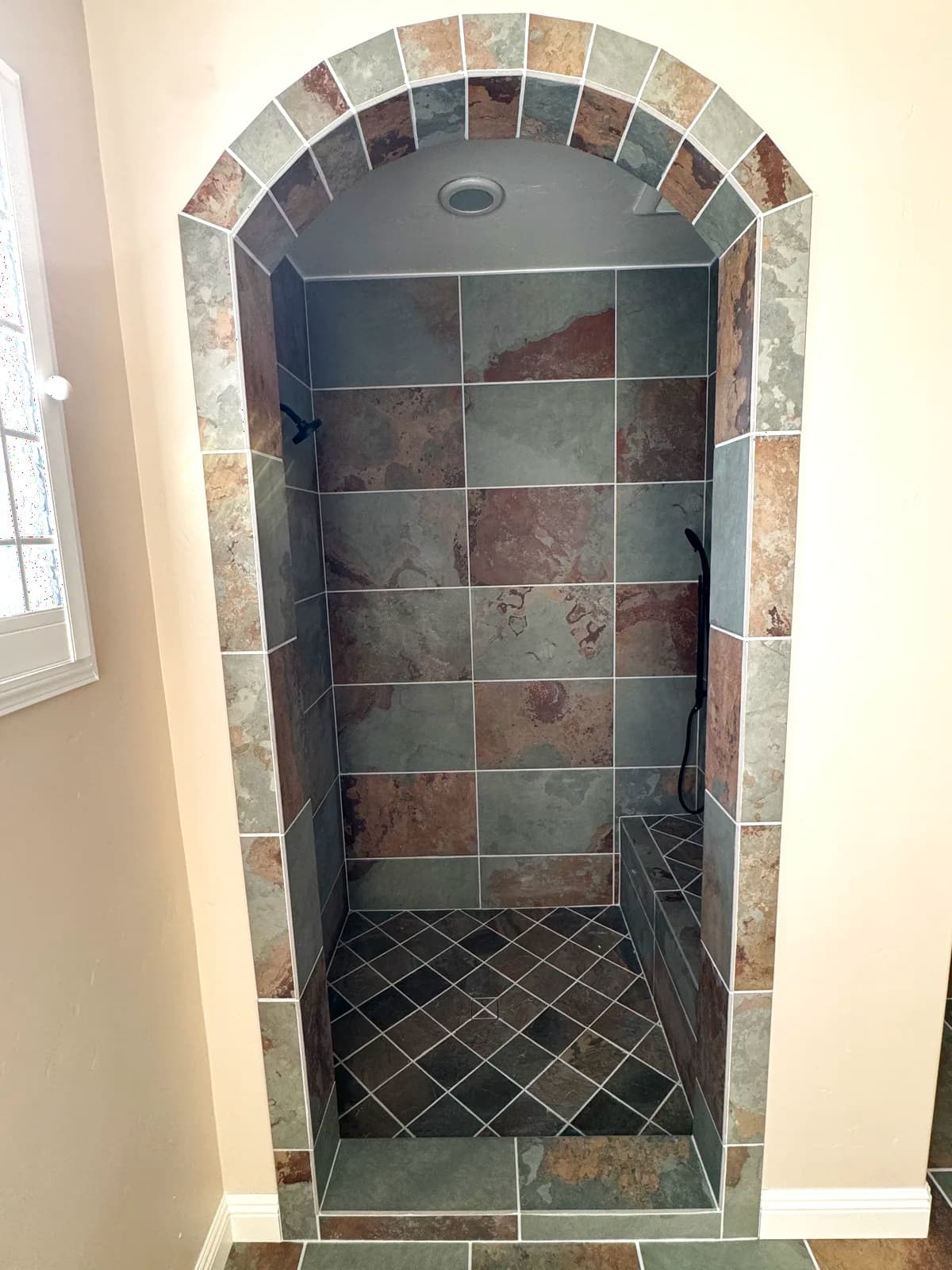 After: arched shower opening finished in slate-look porcelain tile