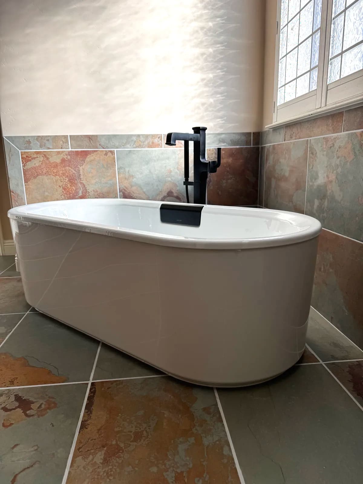After: freestanding tub with floor-mounted matte black tub filler