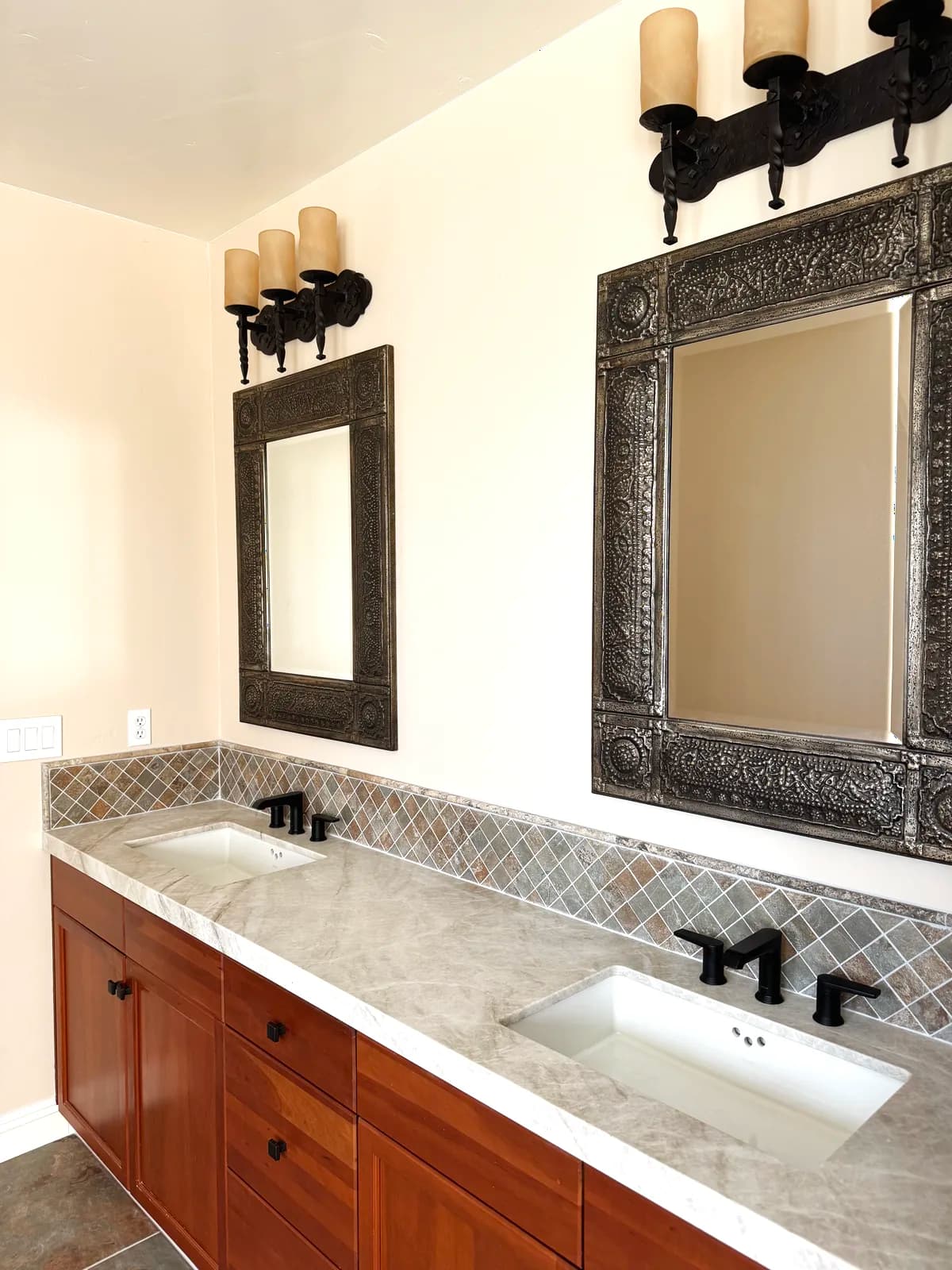 After: vanity with black hardware, framed mirrors and black sconces