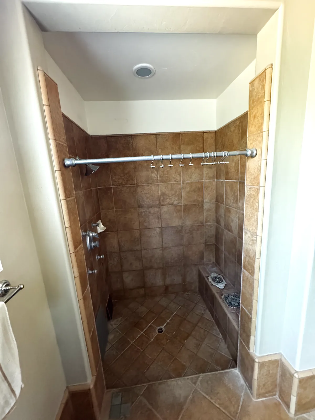 Before: narrow shower stall with small beige tile in an Elk Grove master bathroom