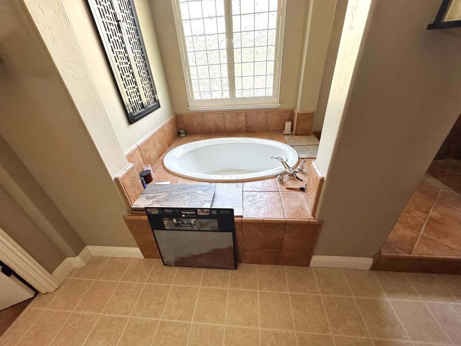 Before: drop-in corner tub in a tiled deck under the window