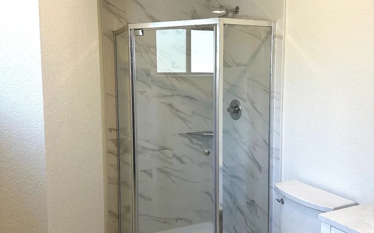 Neo-angle shower in marble-look porcelain with glass enclosure and new white vanity