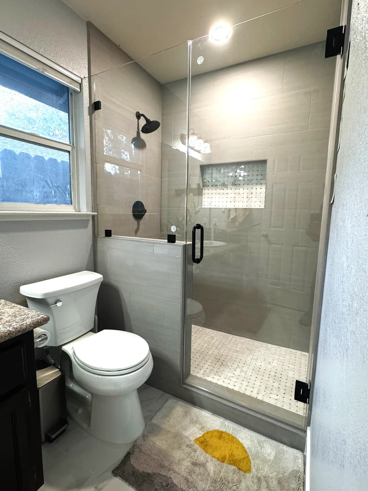 After: rebuilt Loomis shower with grey porcelain tile, mosaic niche, black fixtures and frameless glass over a pony wall
