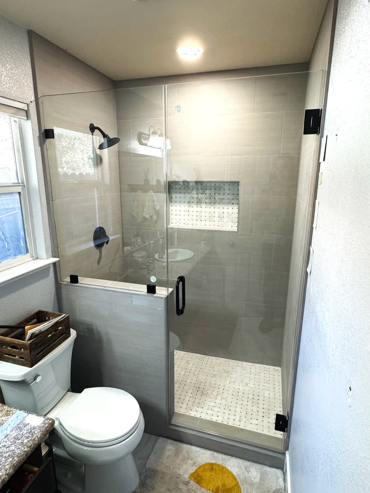 After: frameless glass panel on the tiled pony wall with black fixtures behind