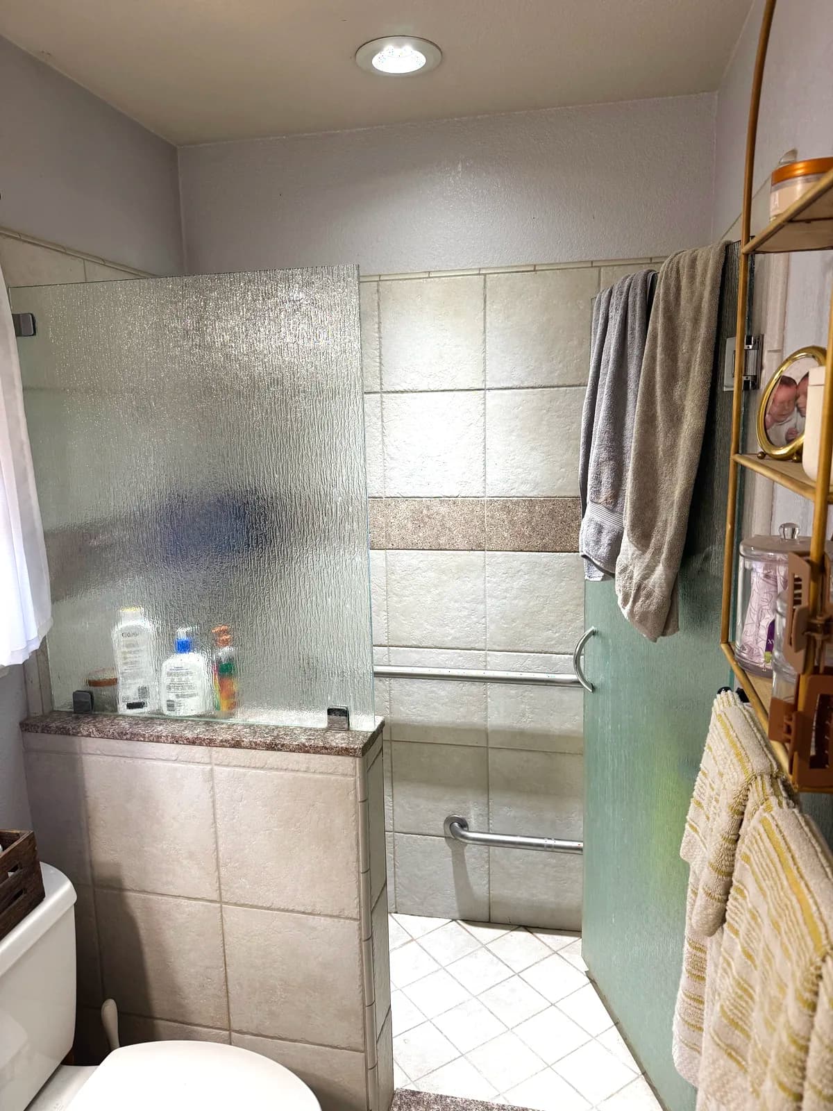 Before: Loomis shower with beige tile, frosted glass door and tiled half wall