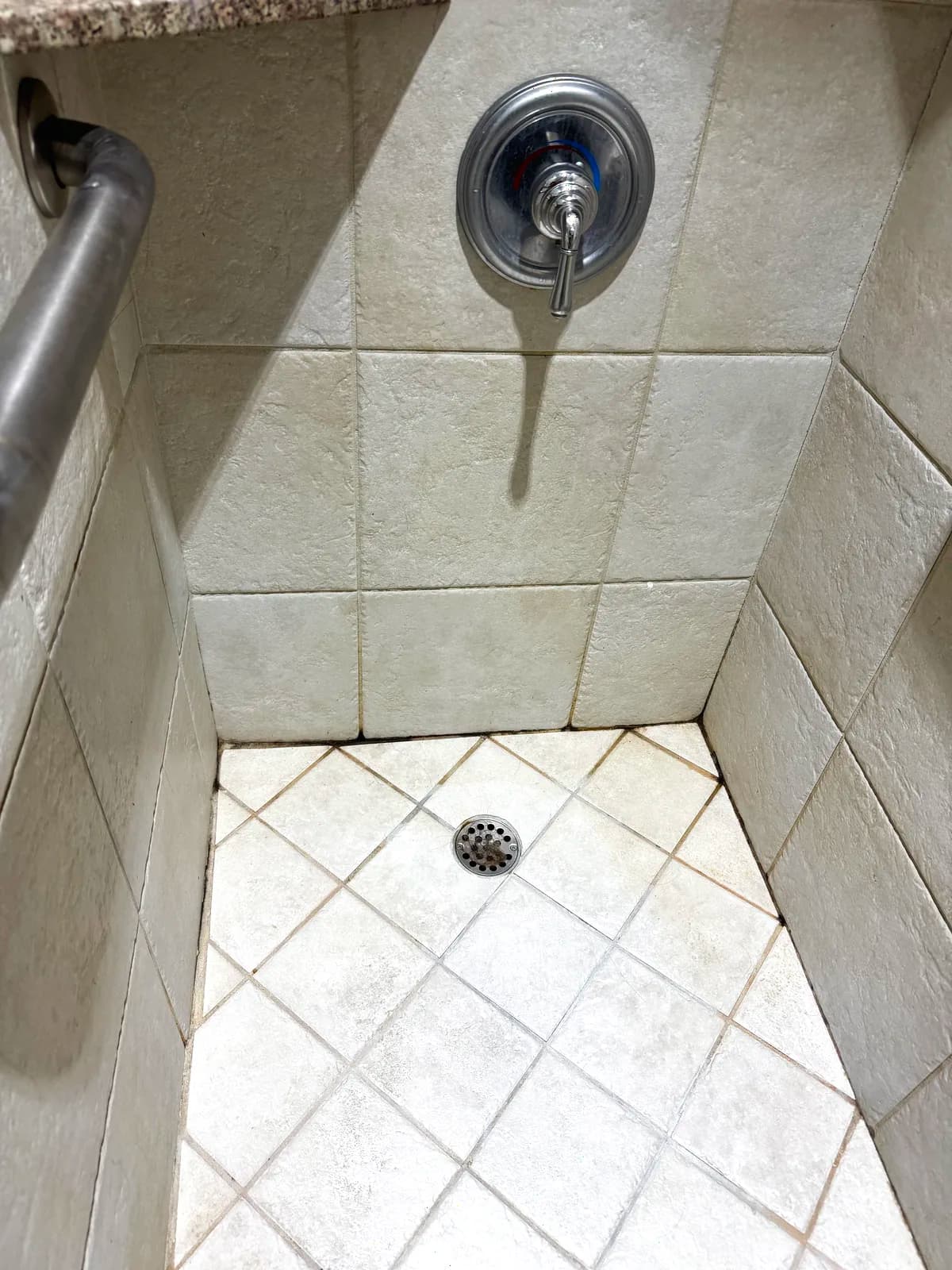 Before: chrome shower valve and diamond-set beige tile shower floor