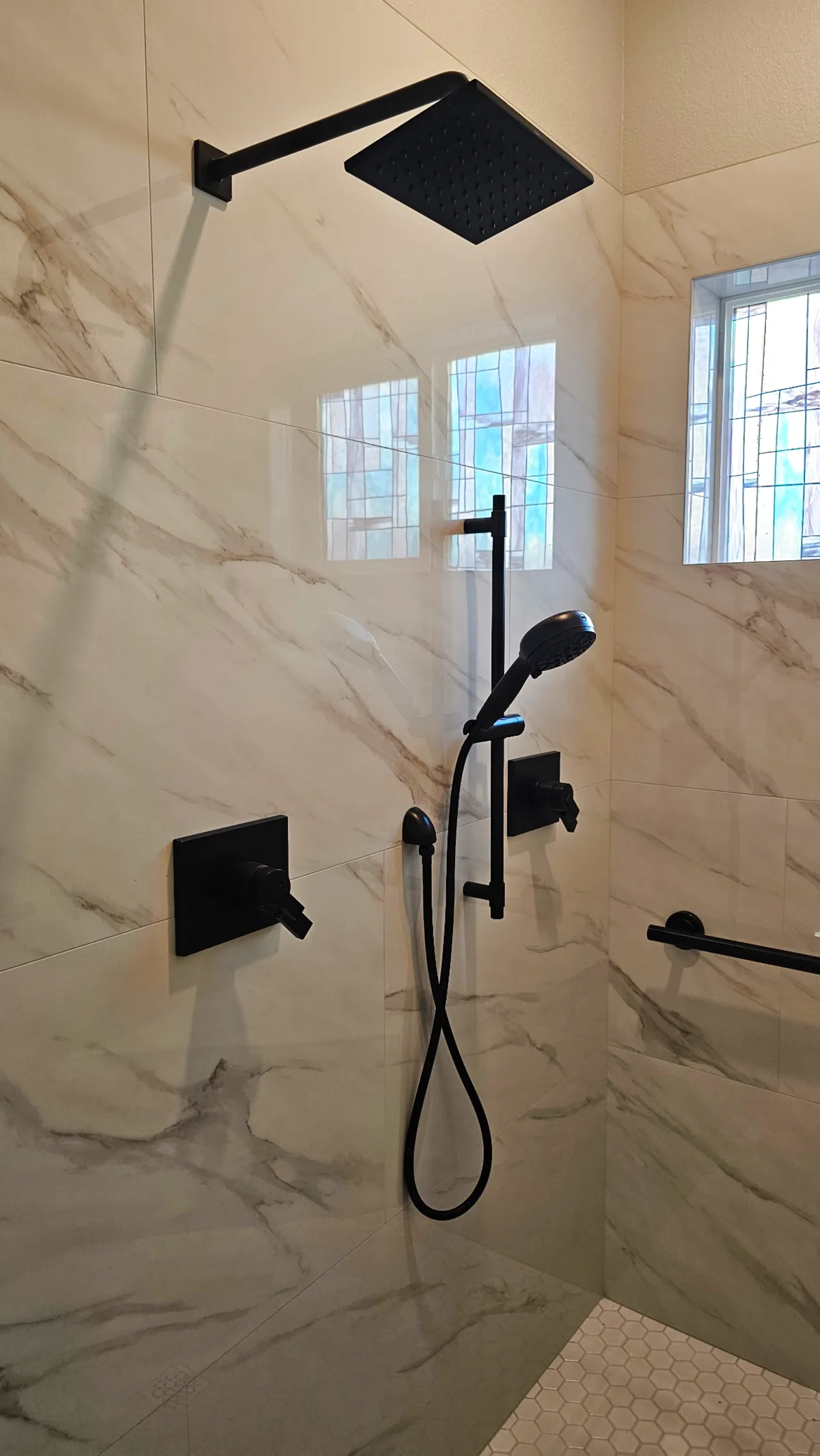 After: Roseville roll-in shower showing matte black 36-inch grab bar on a Calacatta porcelain wall with hex mosaic floor and no shower threshold