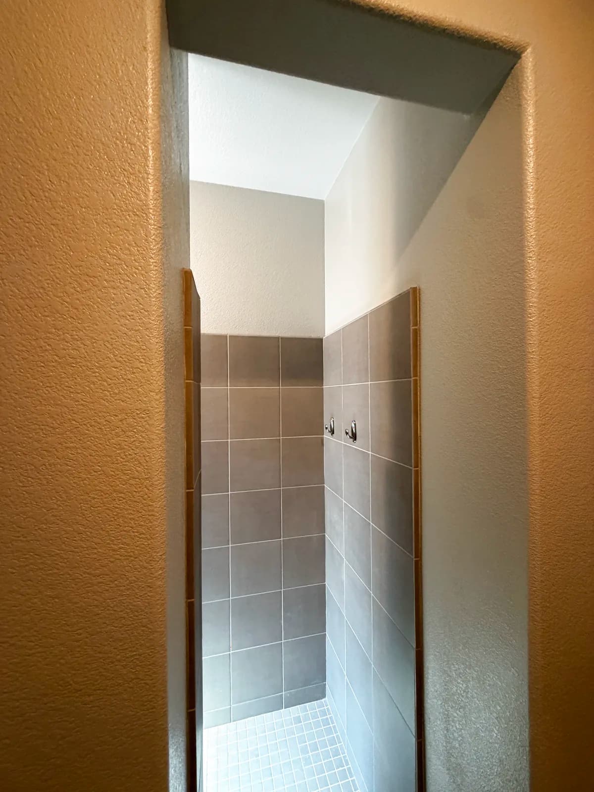 Before: Roseville shower doorway with dated tan tile walls and a narrow opening too tight to roll a wheelchair through