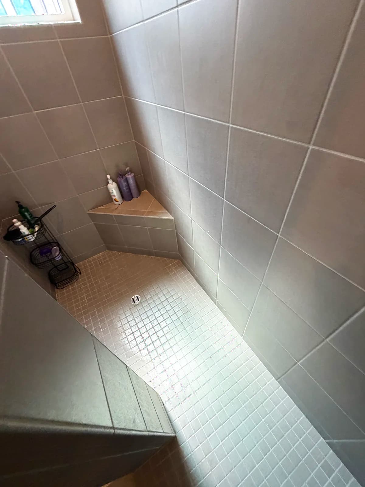 Before: Roseville shower corner showing dated small square tile walls, grout joints throughout and a built-in tile bench with toiletry caddy