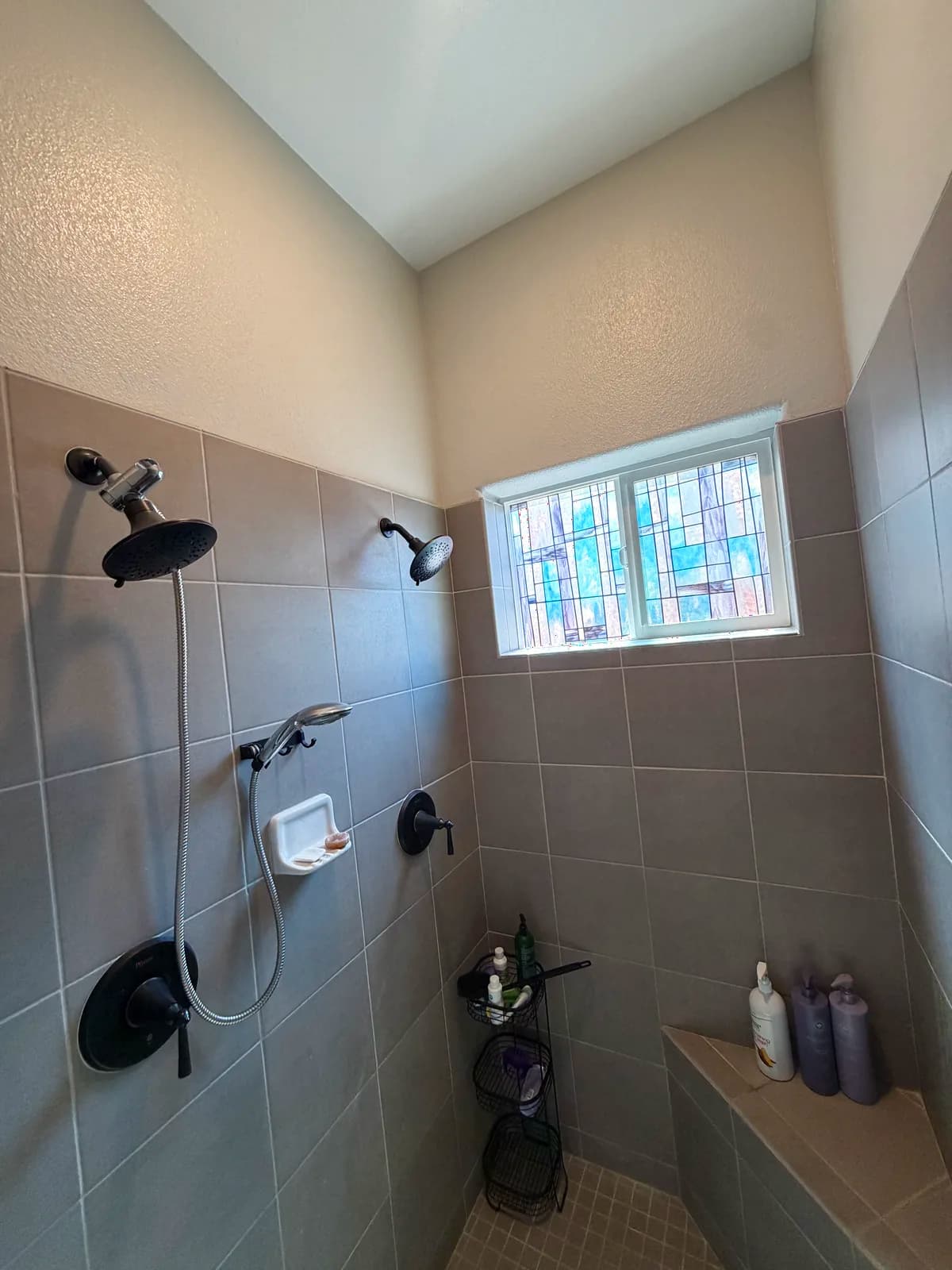 Before: Roseville shower pan with small square tile floor, dated grout and a center drain