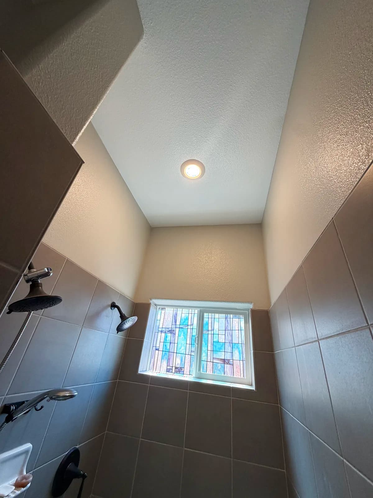 Before: Roseville bathroom showing the pre-demo stained-glass privacy window and dated wall tile around the shower window