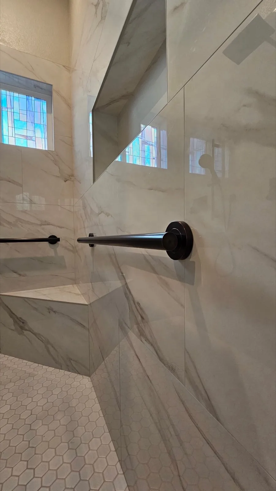 After: Roseville accessible shower with Calacatta marble-look tile, matte black grab bar, built-in bench and hex mosaic floor