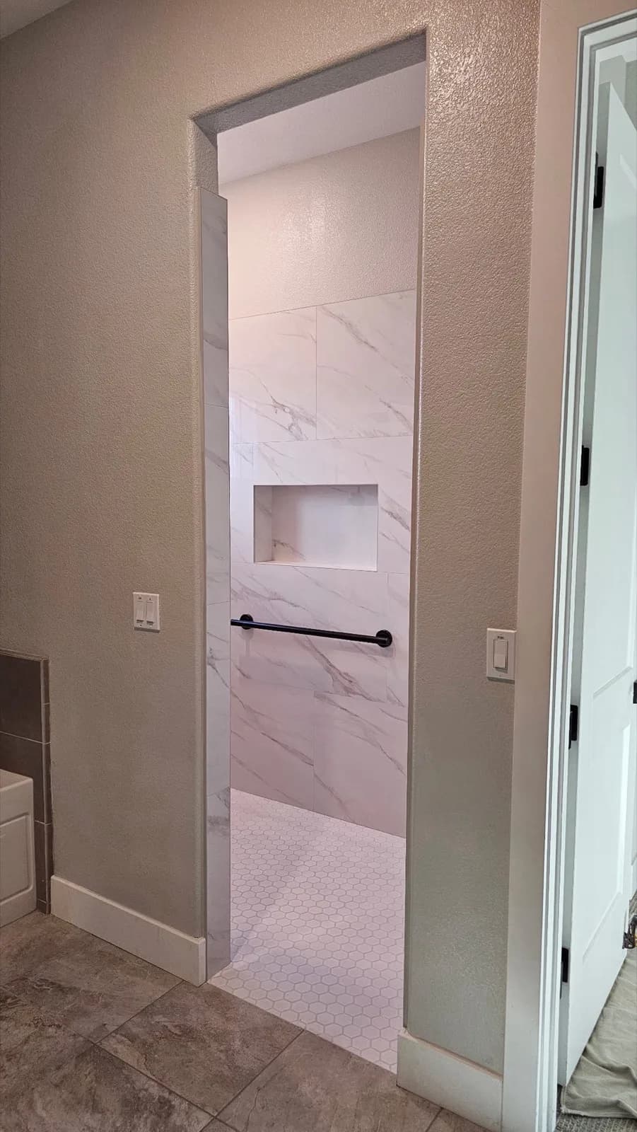 After: Roseville accessible shower wide entry after wall removal — wheelchair-accessible opening with matte black grab bar inside