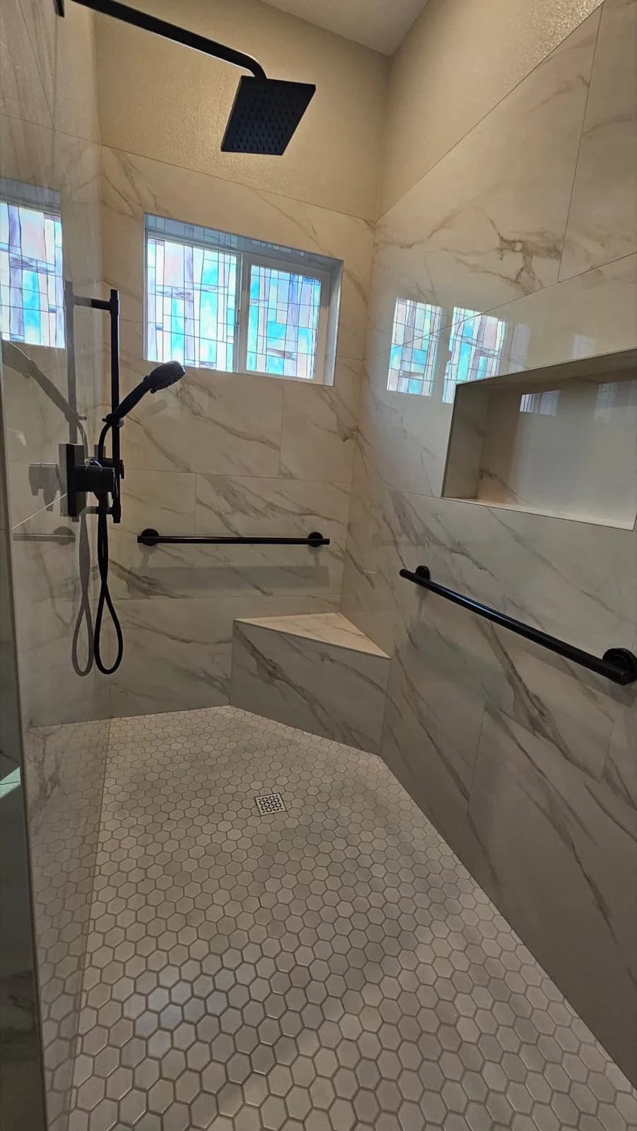 After: Roseville shower custom niche set into marble-look tile with hex mosaic floor visible below