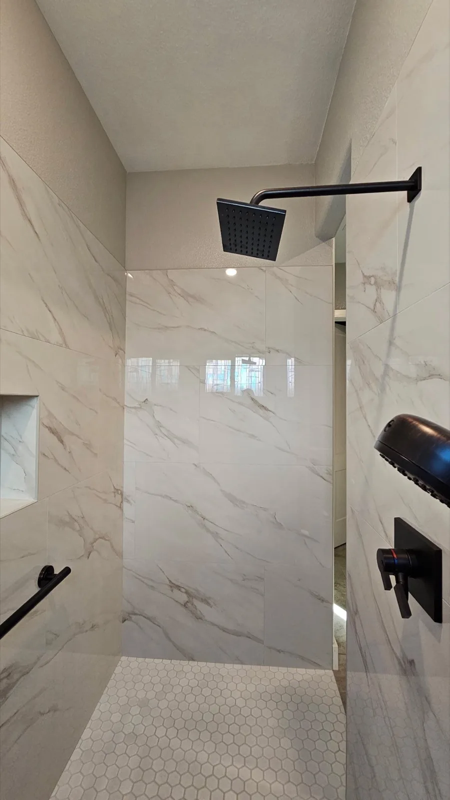 After: Roseville accessible shower showing the full interior width with bench, niche, dual heads and frameless glass panel