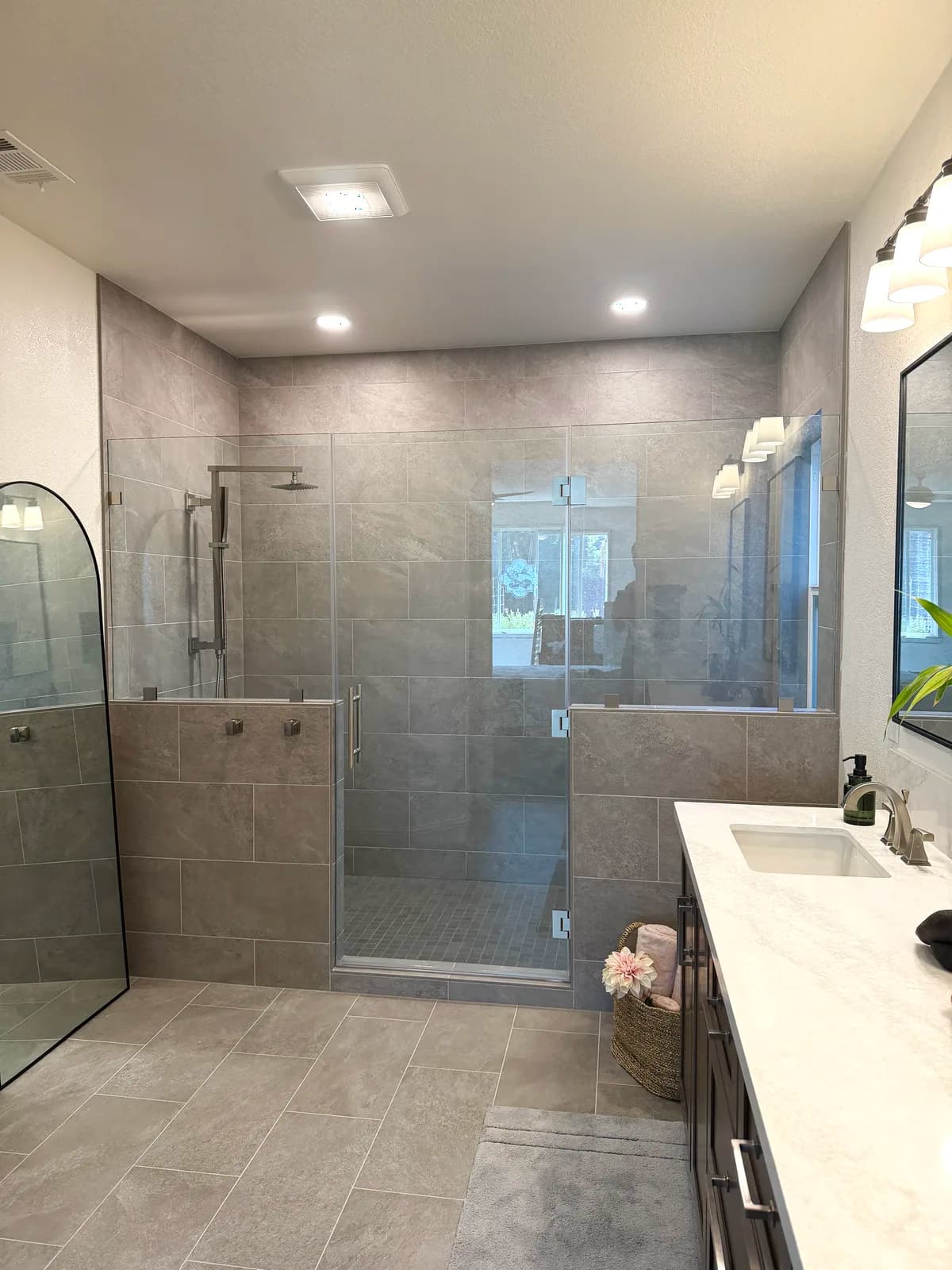 After: large walk-in shower with grey porcelain tile, glass panel and dark shaker vanity in Roseville, CA
