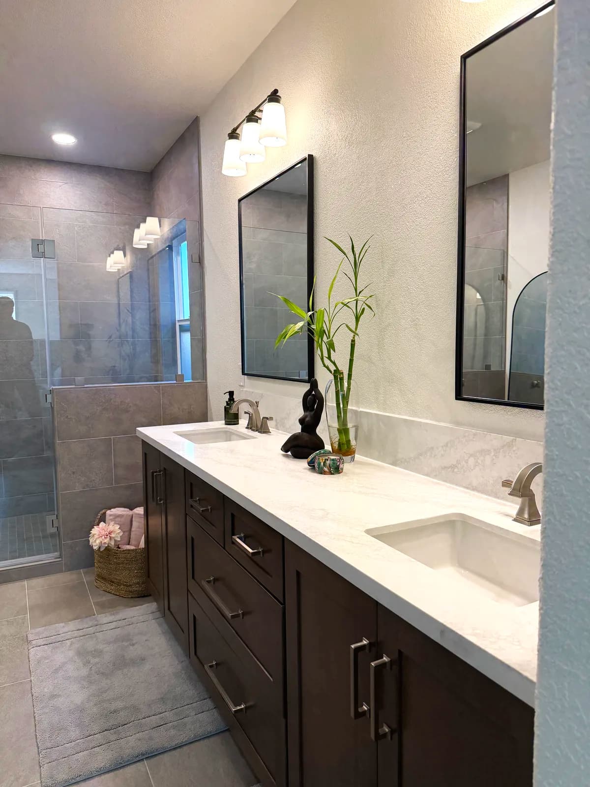 After: dark shaker double vanity with quartz top, black-framed mirrors and sconces