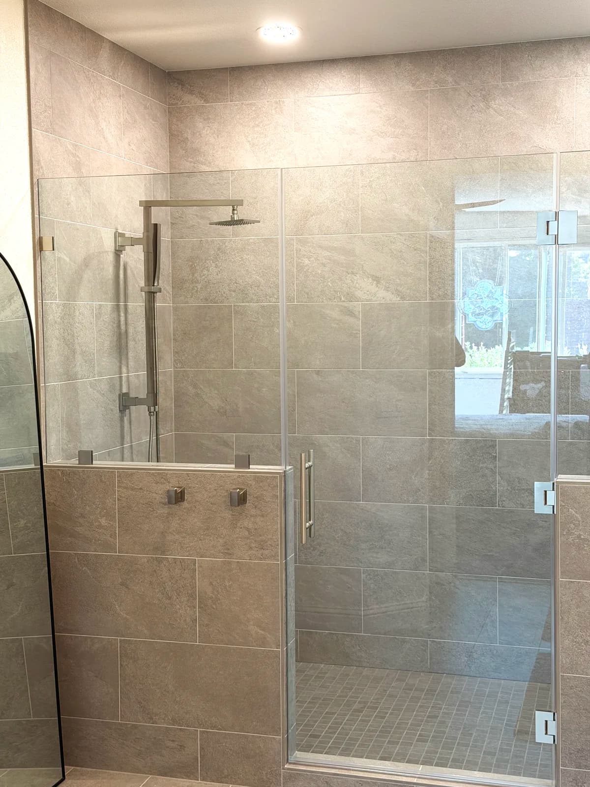 After: tiled bench and glass panel inside the grey porcelain walk-in shower