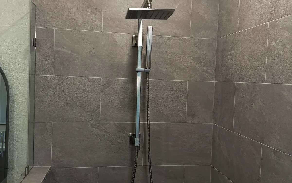 Rain shower head with handheld on a slide bar against grey porcelain tile