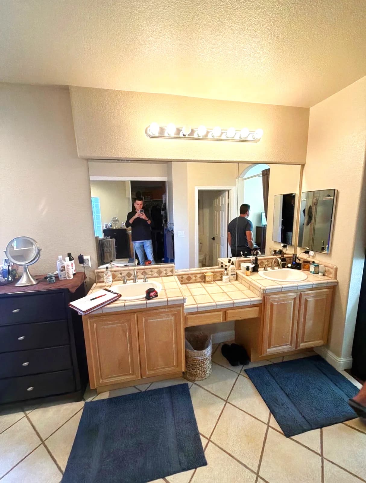 Before: Roseville master bathroom with tile-topped double vanity, plate mirror and Hollywood strip lights