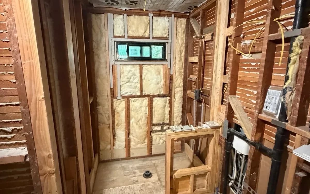 Hallway bathroom in the Arden area of Sacramento, CA stripped to the studs, with the subfloor, shower drain rough-in and vapor barrier visible