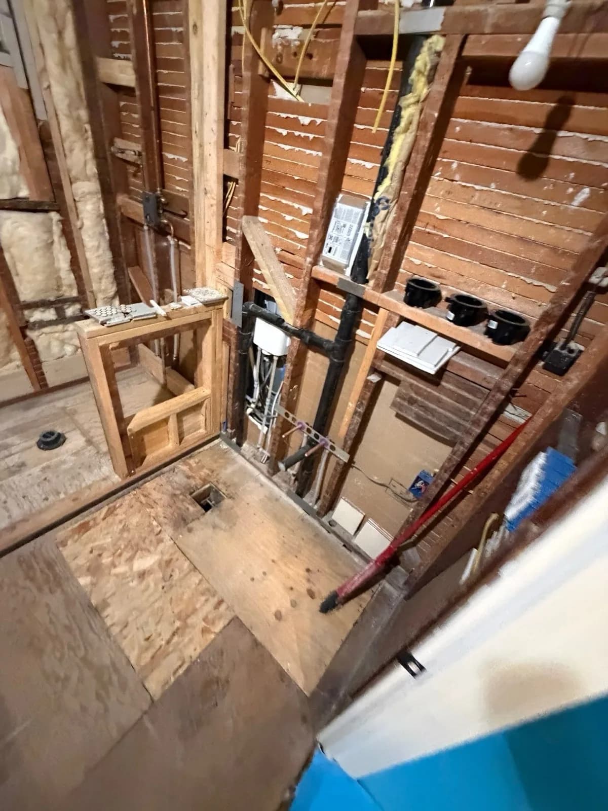 Before: Arden bathroom with bare wood lathe and plumbing stub-outs showing no progress since demo