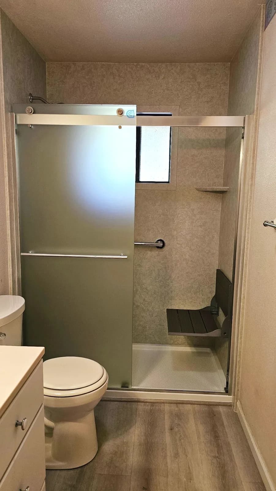 After: Auburn, CA walk-in shower with beige marble-look acrylic walls, fold-down seat and frosted sliding glass door