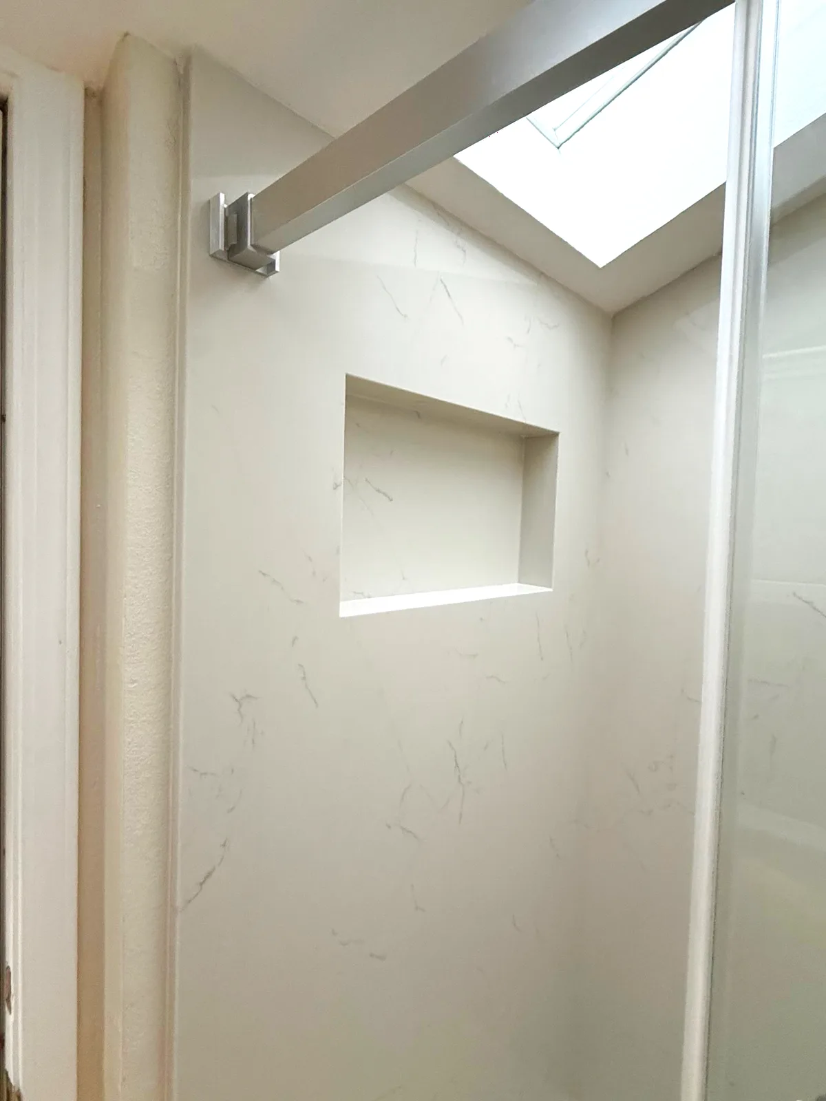 After: solid quartz shower walls with a custom recessed niche under the skylight in Auburn, CA