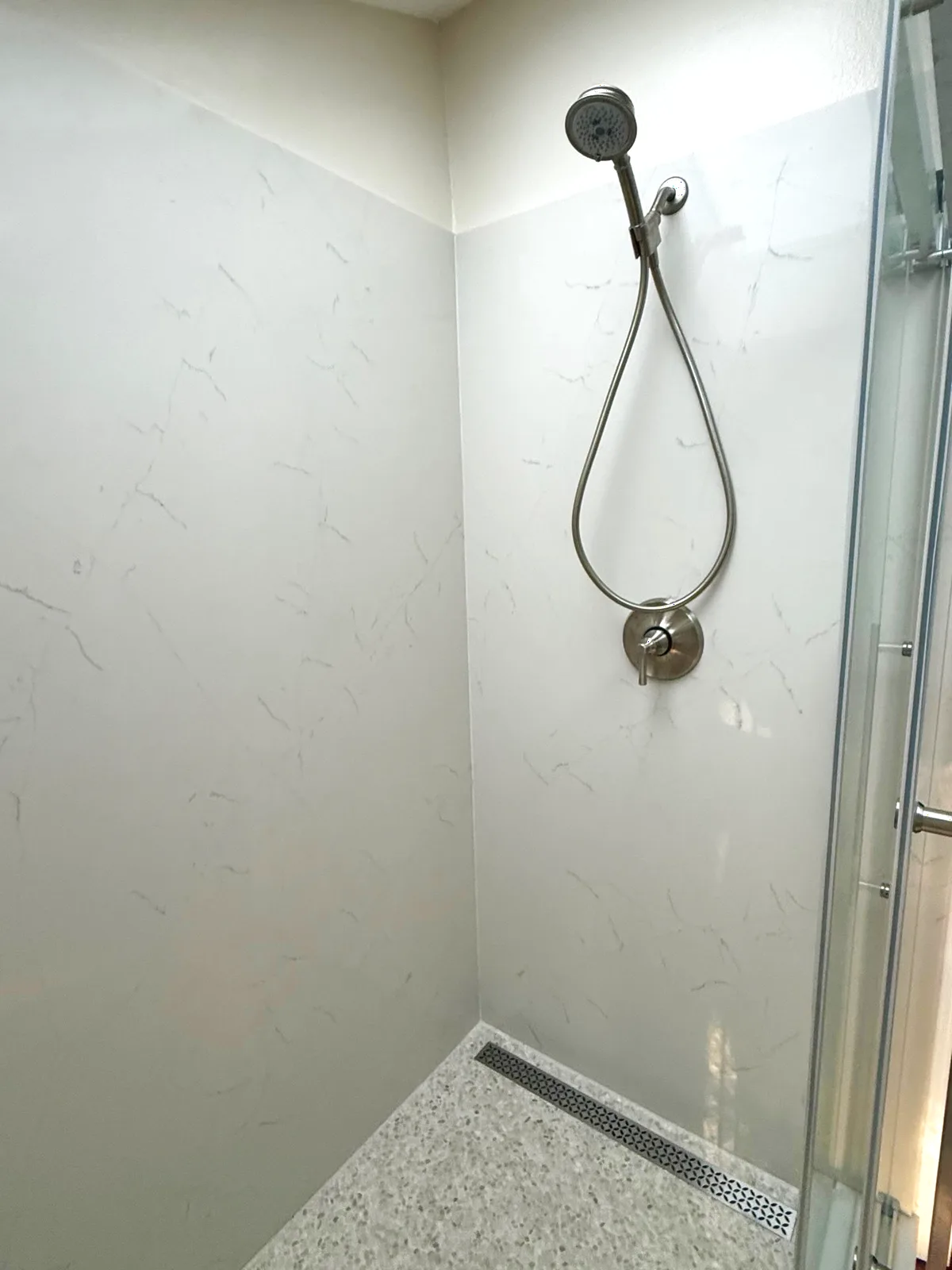 After: brushed nickel handheld shower on seamless quartz panels