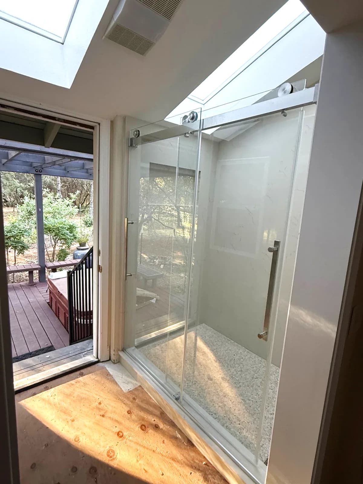 After: frameless glass shower and skylight seen from the bathroom door