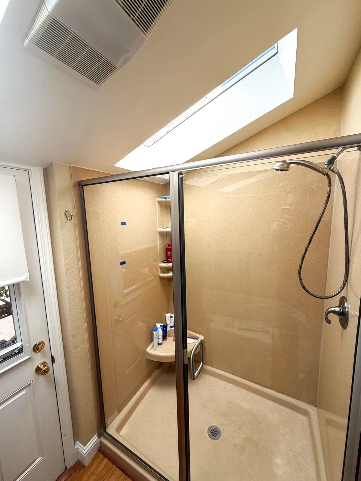Before: framed sliding shower doors and fiberglass surround seen from the bathroom