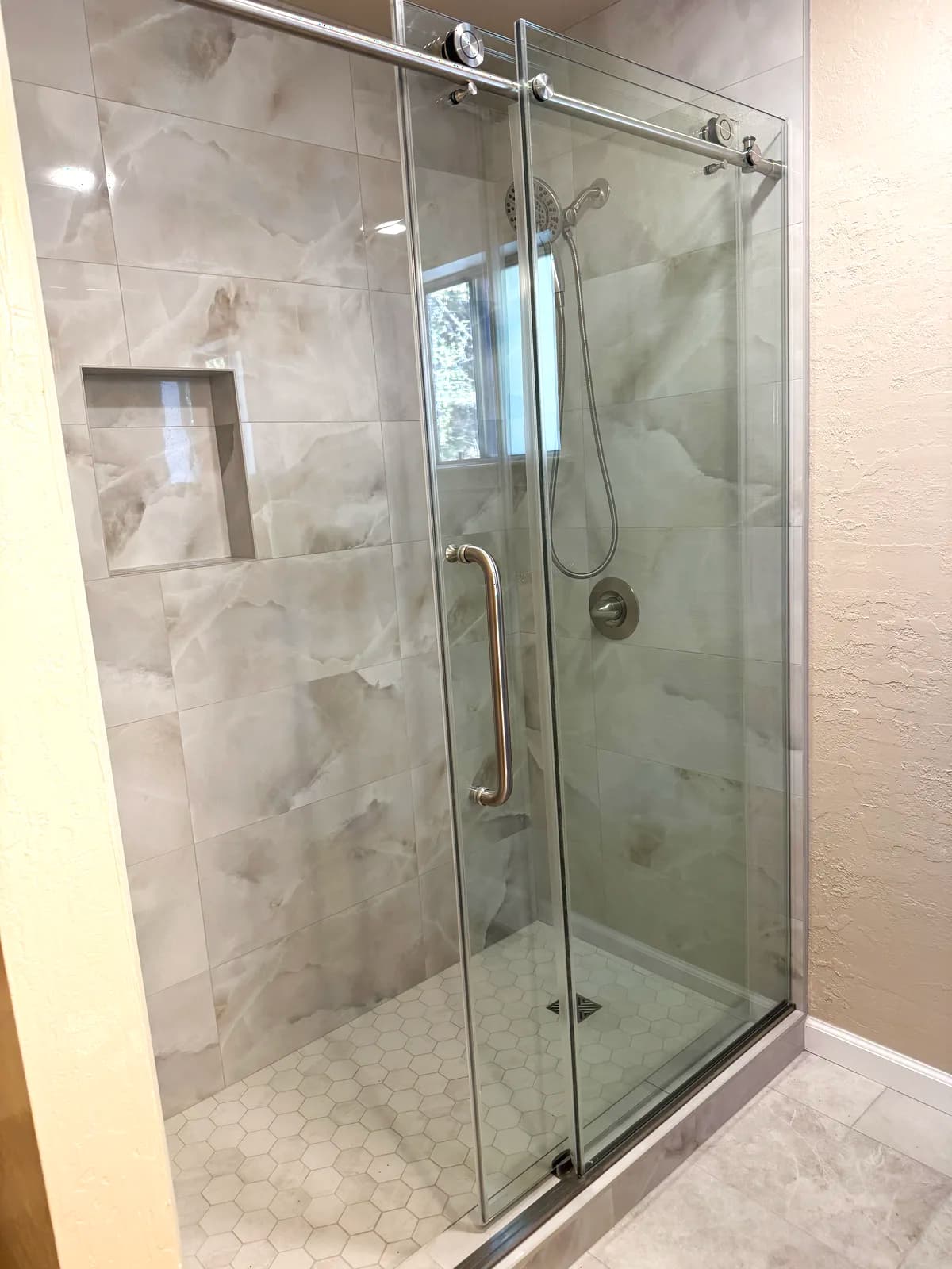 After: walk-in shower with marble-look porcelain, hex mosaic accent wall and frameless sliding glass in Cameron Park, CA