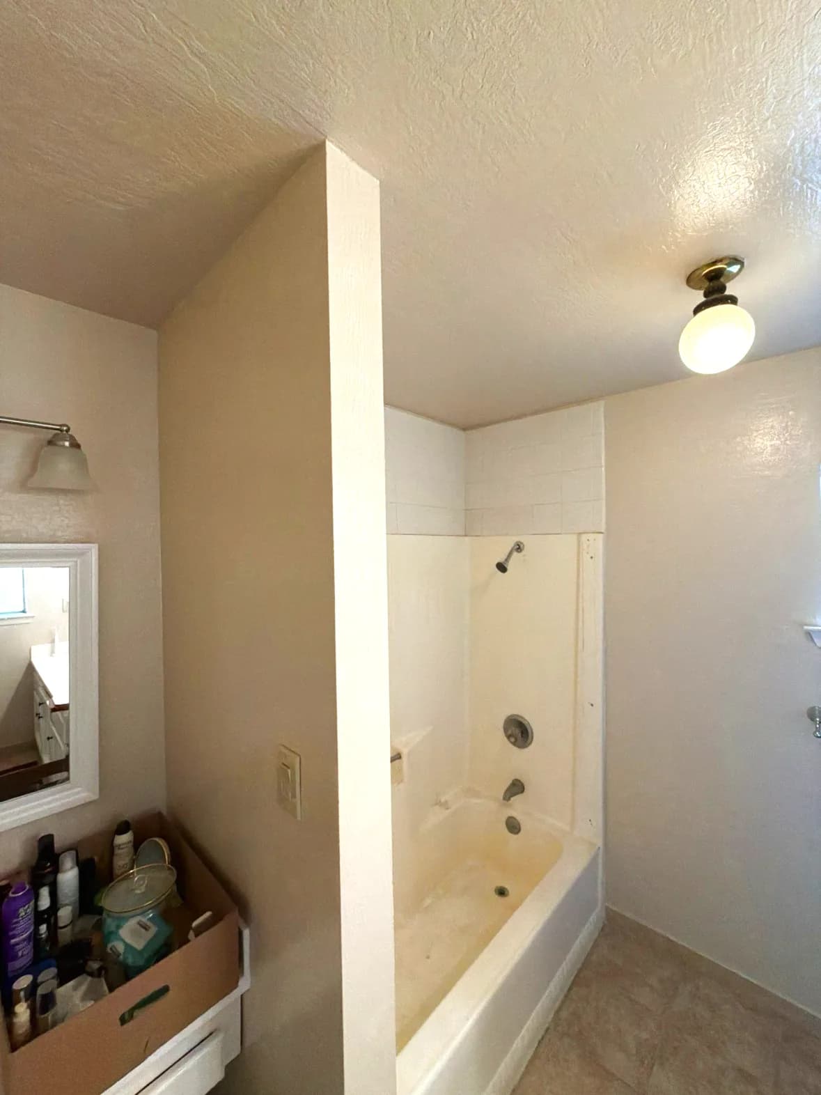 Before: old tub-shower with half wall and single ceiling light in Cameron Park, CA