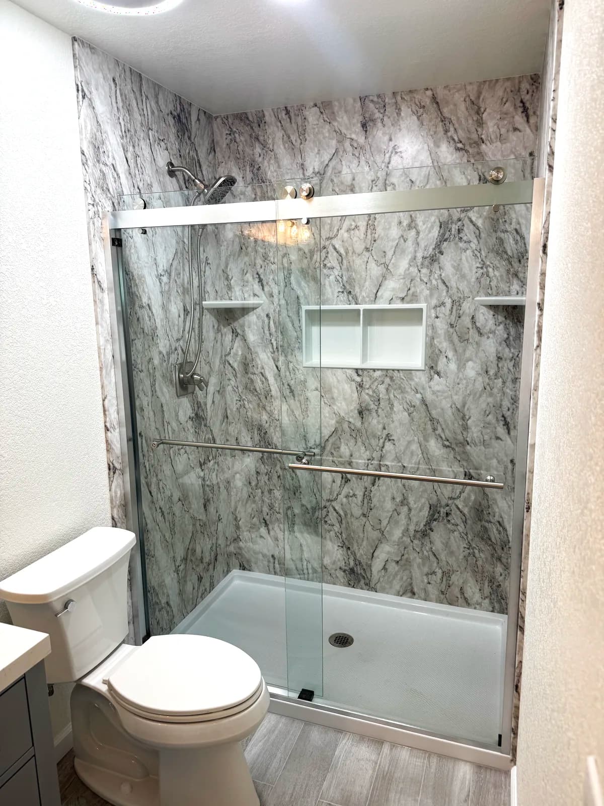 After: Citrus Heights master bathroom with marble-look acrylic shower walls, low-threshold base and sliding glass door