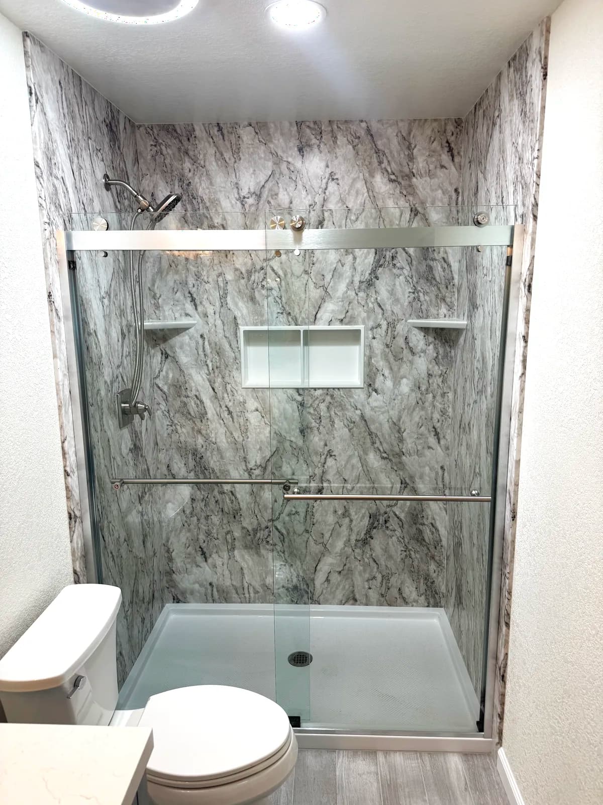 After: chrome-framed sliding glass shower door and twin recessed niche on acrylic panels in Citrus Heights, CA