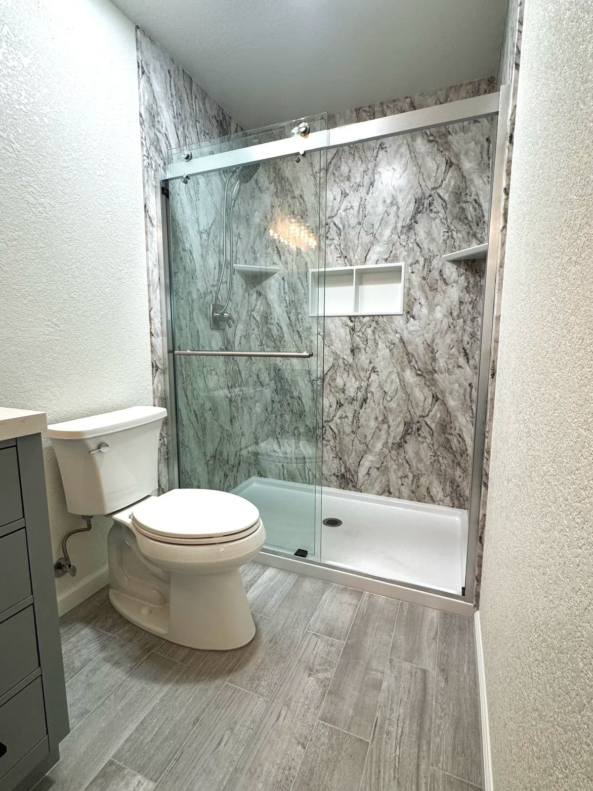 After: new toilet, wood-look plank flooring and the acrylic-walled shower in a Citrus Heights master bathroom