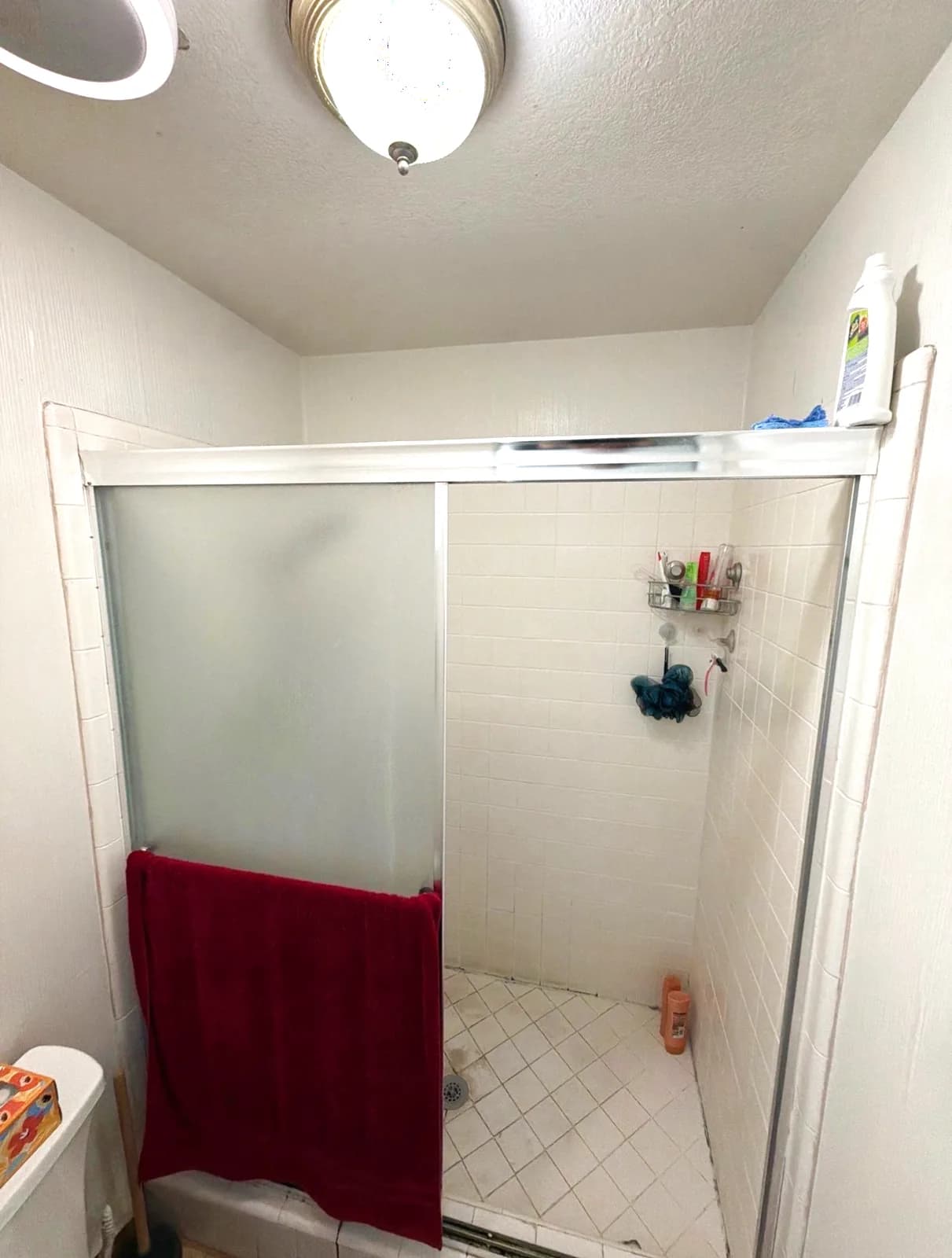Before: Citrus Heights master bathroom shower with framed sliding glass doors, small white wall tile and a tiled floor pan